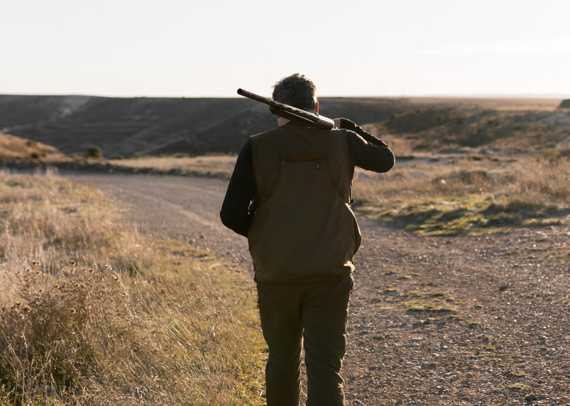 Hunter man is walking with the shotgun on his shoulder